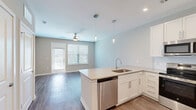 Located at 4600 Bakers Blessing Ln in Summerville, SC, this single-floor, 2-bedroom, 1-bathroom home offers a thoughtfully designed layout with modern finishes throughout. The open-concept kitchen and living area serves as the heart of the home, featuring white shaker-style cabinetry, a peninsula with a undermount sink and light quartz countertops, stainless steel appliances including a dishwasher, microwave, range, and French door refrigerator, and elegant pendant lighting. Wood-look plank flooring runs throughout the main living areas, while the living room benefits from natural light via large windows and a glass-panel door leading outside, complemented by a ceiling fan overhead. The primary bedroom is generously proportioned, carpeted for comfort, and includes a ceiling fan and ample natural light. A walk-in closet with multi-tier wire shelving provides excellent storage. The second bedroom also features carpet, neutral tones, and a well-positioned window. The full bathroom is clean and contemporary, with a tub-shower combination clad in white subway tile, a vanity with quartz countertop, and wood-look flooring. Neutral paint tones and consistent design choices lend the entire space a cohesive, modern aesthetic.