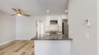 Located at 887 Saint Charles Dr in Thousand Oaks, CA, this thoughtfully updated 2-bedroom, 1-bathroom single-floor unit offers a clean, modern aesthetic throughout. Light wood-tone flooring flows seamlessly across the open layout, complementing the bright, neutral color palette on the walls and ceilings.

The kitchen is a standout feature, designed in a galley style with white shaker cabinetry, dark countertops, a white subway tile backsplash, and a full suite of stainless steel appliances including a gas range, over-the-range microwave, and French door refrigerator. A peninsula with a built-in sink extends into the open living area, creating a natural divide while maintaining connectivity between the kitchen and living room.

The living room is spacious and airy, equipped with a wall-mounted mini-split unit and a modern ceiling fan with a gold finish. Natural light fills the room, adding to the comfortable ambiance.

The primary bedroom is generously sized, featuring a large sliding glass window with outdoor views of mature trees, and a mirrored sliding closet. The second bedroom also benefits from natural light and a sizable window. Three closets are distributed throughout the unit.

The bathroom is clean and functional, featuring a full tub-shower combination with brushed nickel fixtures and white cabinetry with dark countertops. A dedicated in-unit laundry area with a stacked washer and dryer adds everyday convenience.