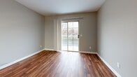 Located at 215 N Baird Ln in Murfreesboro, Tennessee, this one-bedroom, one-bathroom unit offers a functional single-floor layout with a thoughtful mix of finishes throughout. The living room features warm wood-look vinyl flooring and is bathed in natural light through a full sliding glass door that opens to a private balcony, providing pleasant outdoor views. A six-panel entry door with brushed nickel hardware adds a classic touch to the entryway. The kitchen is efficiently designed in a galley style, showcasing rich warm-toned wood cabinetry across both upper and lower sections, white countertops, and black appliances including an electric range and refrigerator. A double basin sink and additional pantry-style storage round out the kitchen's practical features. The bedroom offers cozy carpeted flooring in neutral tones, soft gray walls, and a window that brings in natural light. A dedicated closet provides storage within the bedroom. The bathroom is clean and straightforward, featuring wood-look flooring, a full tub-shower combination, a vanity with a light-toned countertop, and brushed nickel fixtures throughout. Neutral gray walls are consistent across the unit, creating a cohesive and understated aesthetic throughout this well-organized space.