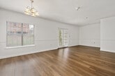 This thoughtfully laid-out one-bedroom, one-bathroom unit features hardwood-style flooring throughout, crisp white walls, and textured ceilings that lend a classic, clean aesthetic. A welcoming hallway connects the main living spaces, lined with panel doors providing access to the closet, bathroom, and laundry room. The open-concept living and dining area is generously proportioned, filled with natural light from large windows dressed with blinds, and accented by an elegant chandelier. A convenient pass-through window connects the living area to the kitchen, which features rich dark-wood cabinetry, light countertops, and stainless steel appliances including a refrigerator and dishwasher. Adjacent to the kitchen, the dedicated laundry room houses a full-size washer and dryer alongside an electrical panel. The bedroom is a comfortable retreat, equipped with a ceiling fan with light fixture, a window for natural light, and access to a dedicated closet. The full bathroom offers a single-sink vanity with dark wood cabinetry, a large mirror with vanity lighting, and a full tub-shower combination. Throughout the unit, consistent finishes and a neutral color palette create a cohesive, move-in-ready living environment.