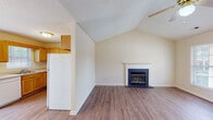 Located at 632 Harkey Rd in Sanford, NC, this single-story home offers a well-designed layout with a welcoming mix of comfort and functionality. The living room serves as the heart of the home, showcasing soaring vaulted ceilings, a classic fireplace with a white-trimmed mantle and dark slate surround, and durable hardwood-style flooring that adds warmth throughout the main living areas. The open flow connects seamlessly to the dining area, which is illuminated by a brass chandelier and features a glass-paned door that invites natural light and outdoor views. The kitchen is outfitted with warm honey-toned wood cabinetry, white appliances including a range, microwave, dishwasher, and refrigerator, along with a double sink and a window overlooking the outdoors. The bedrooms are carpeted for comfort; the primary bedroom benefits from vaulted ceilings, a ceiling fan, and direct access to an en-suite bathroom, while additional bedrooms are bright and generously sized with windows providing natural light. Two full bathrooms serve the home, each featuring a tub/shower combination and hardwood-style flooring. Throughout, the neutral color palette and textured ceilings create a clean, move-in-ready atmosphere suitable for a variety of lifestyles.