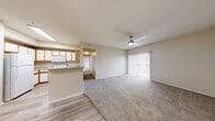 Located at 3703 Wurzbach Rd in San Antonio, Texas, this single-floor residence offers a practical and comfortable layout with two bedrooms and two bathrooms. The open-concept living room features neutral-toned walls, soft carpet flooring, and a ceiling fan with integrated lighting, creating a bright and airy atmosphere. A pass-through counter connects the living area to the kitchen, which is equipped with white cabinetry accented by warm wood trim, granite-style countertops, white appliances including a refrigerator, electric range, and microwave, and easy-to-maintain wood-look flooring. The primary bedroom is generously sized, with a ceiling fan, a large window that brings in natural light, and access to a private en-suite bathroom. The en-suite features a granite-topped vanity with a wood-framed cabinet, a full tub-shower combination, and wood-look flooring. The second bedroom is carpeted and includes a ceiling fan, a window with natural light, and a double-door closet offering ample storage. The second bathroom provides additional storage with overhead cabinetry. A hallway connects the main spaces efficiently, and the overall warm, neutral color palette lends a clean and cohesive feel throughout the home.