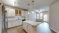 Located at 180 Woodruff Rd in Greenville, SC, this well-appointed one-bedroom, one-bathroom residence offers a thoughtfully designed single-level layout. The open-concept kitchen and living area serves as the heart of the home, where light wood-look flooring flows throughout. The kitchen is outfitted with crisp white cabinetry, a classic subway tile backsplash, gleaming granite countertops, a large center island with pendant lighting overhead, and a full suite of stainless steel appliances including a refrigerator, range, microwave, and dishwasher. Track lighting adds a modern touch to the space. The living area benefits from natural light provided by multiple windows and a sliding glass door, complemented by a ceiling fan. The generously sized primary bedroom features soft carpeting, a ceiling fan, and a dedicated walk-in closet. The bathroom is a refined retreat, complete with wood-look tile flooring, a granite-topped vanity, built-in shelving, and a frameless glass walk-in shower adorned with elegant marble-style tile. Neutral wall tones and clean white trim throughout create a cohesive, move-in-ready aesthetic.