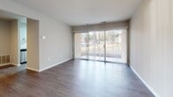 Located at 7000 Coachman Lane in Henrico, Virginia, this single-story unit offers a thoughtfully updated interior with a clean, contemporary aesthetic throughout. The living area is highlighted by smooth wood-style laminate flooring and a large sliding glass door fitted with vertical blinds, allowing generous natural light to fill the space while providing access to the outdoors. Neutral wall tones and white trim create a bright, cohesive backdrop throughout the main living areas.

The kitchen has been updated with white shaker-style cabinetry accented by matte black hardware, white quartz countertops, and a classic subway tile backsplash. A stainless steel single-basin sink with a matte black pull-down faucet is paired with stainless steel appliances, including a gas range, microwave, and dishwasher, offering both style and functionality.

A hallway with wood-style flooring connects the main living area to the private spaces, which include carpeted bedrooms featuring neutral tones and ample natural light from well-placed windows. The bathroom is finished with a white shaker vanity, quartz countertop, oil-rubbed bronze fixtures, a large mirror, and a tiled shower-tub combination, maintaining the unit's consistent modern sensibility.
