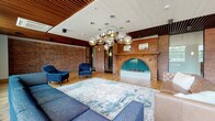 Located at 165 Thorndike, this thoughtfully designed single-floor amenity space masterfully combines industrial heritage with contemporary style. Warm hardwood floors in a herringbone pattern run throughout, complemented by exposed brick walls and striking slatted wood ceiling details that add depth and warmth to every zone.

The lounge area serves as a dramatic focal point, anchored by an ornate wood-mantled fireplace with teal tile detailing. Clustered mercury glass globe pendant lights illuminate plush blue armchairs and a leather sofa, creating an inviting and sophisticated gathering space. Generous large-paned windows line the perimeter, flooding the interior with natural light and offering views of the surrounding neighborhood.

An open game room features a full-size pool table beneath bold slatted pendant fixtures, alongside a sleek marble-topped bar station equipped for entertaining. The dining area accommodates a large group around a dark wood table with industrial metal chairs, all beneath eye-catching wire-frame geometric chandeliers.

Glass-paneled partitions define flexible zones while maintaining an open, airy feel across the expansive floor plate. The overall ambiance is a refined balance of historic character and modern amenity, making this a highly functional and visually compelling communal space.