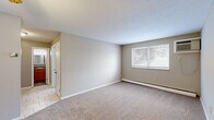 Located at 680 Smith Ct in Rocky River, OH, this one-bedroom, one-bathroom unit offers a practical and well-organized single-floor layout. The living room is a comfortable, open space finished with neutral-toned carpet and warm beige walls, bathed in natural light from a large window with views of surrounding greenery. A baseboard heating system runs along the exterior wall, and a wall-mounted air conditioning unit ensures year-round climate control. The layout flows from the living area into the bedroom, which also features soft carpeting, a window with outdoor views, and its own baseboard heating. Two closets provide ample storage throughout the unit. The kitchen is equipped with warm wood-toned cabinetry, a freestanding electric range, and durable tile flooring, offering an efficient and functional cooking space. The bathroom features a full tub-and-shower combination with classic white tiling accented by a bold black tile border, adding a clean, timeless aesthetic. Textured ceilings are present throughout the unit, contributing to the overall character of the space. The floorplan model reveals a compact yet thoughtfully arranged layout, making efficient use of every area. This unit is a straightforward, move-in-ready space in a well-established Rocky River location.