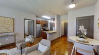 This single-story, 2-bedroom, 2-bathroom residence offers a thoughtfully designed layout that maximizes its footprint. The open-concept main living area combines the kitchen, dining, and living spaces into one cohesive zone anchored by rich hardwood flooring. The kitchen features warm cherry-toned cabinetry, granite-style countertops, stainless steel appliances including a refrigerator and microwave, and a peninsula with an integrated sink that doubles as a breakfast bar illuminated by pendant lighting.

The living area benefits from multiple windows that invite natural light, complemented by a ceiling fan overhead. An arched architectural detail frames the hallway connecting the main living area to the bedrooms, adding a subtle design element.

Both bedrooms are carpeted and equipped with ceiling fans and windows. The primary bedroom is a comfortable size and provides direct access to its own bathroom, which features a single vanity with granite-style countertops and hardwood-style flooring. The second bathroom includes a full soaking tub with shower, matching cabinetry, and granite countertops. Each bedroom is served by a dedicated closet with wire shelving systems, providing organized storage throughout the unit.