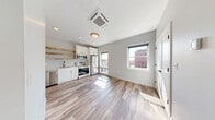 Located at 25 Lowell St in Manchester, NH, this thoughtfully designed one-bedroom, one-bathroom unit makes excellent use of its compact footprint. The open-plan kitchen and living area is anchored by light wood-tone flooring and neutral gray walls, creating a bright and cohesive atmosphere. A ceiling-mounted HVAC unit and recessed lighting ensure year-round comfort, while windows facing the surrounding urban streetscape invite natural light throughout the day.

The kitchen is well-appointed with white shaker cabinetry, warm wood floating shelves, and a full suite of stainless steel appliances including a French-door refrigerator, electric range, built-in microwave, and dishwasher — maximizing both style and function in the space.

The bedroom features rich hardwood flooring, a distinctive gray grid-paneled accent wall, a double-door closet, and a window with views of the neighboring brick architecture. An entry hallway includes built-in coat hooks and a shelf, offering practical storage. The bathroom is clean and modern, with a walk-in shower accented by subway tile and a matte black curtain rod. In-unit stacked laundry is also included, adding a notable level of convenience to this efficiently laid-out urban residence.