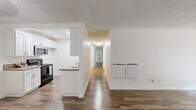 Located along Pacific Coast Highway in Torrance, California, this two-bedroom, two-bathroom residence offers a thoughtfully laid-out single-floor plan with a clean, neutral aesthetic throughout. Wood-style flooring runs through the main living areas, including the spacious living room, which features a sliding glass door fitted with vertical blinds that invite natural light and provide outdoor access. A ceiling fan adds comfort to the entryway area nearby.

The kitchen is outfitted with white cabinetry, granite-style countertops, a stainless steel sink, and a range, offering a practical and bright cooking space with recessed lighting overhead. A peninsula-style counter connects the kitchen to the main corridor, enhancing the open flow of the layout.

Both bedrooms feature plush wall-to-wall carpeting and sliding mirrored closet doors with gold-tone frames, providing ample storage. The primary bedroom is generously sized with its own dedicated closet space. Each of the two bathrooms is finished with granite-style countertops, white vanity cabinetry, large mirrors, and wood-style flooring, creating a cohesive and polished look. Textured ceilings are present throughout the home, adding a classic residential character to the overall space.
