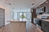 Located steps from Centennial Olympic Park in the heart of Atlanta, this single-floor residence offers a contemporary design with clean lines and a bright, open layout. The kitchen is a standout feature, equipped with sleek dark cabinetry, stainless steel appliances including a refrigerator, microwave, and range, and a large center island with a quartz countertop and undermount sink — ideal for both cooking and entertaining. Hardwood-style flooring flows throughout the main living and kitchen areas, adding warmth to the modern aesthetic.

The bedrooms are carpeted for comfort and feature large sliding glass doors that invite abundant natural light and provide views of the surrounding Atlanta skyline and greenery. Ceiling fans add a functional touch to the bedroom spaces. The bathrooms are well-appointed, with one featuring a frameless glass walk-in shower with white tile surround, and another offering a floating dark vanity with a white quartz countertop, large mirror, and warm wood-tone flooring. Additional storage is provided via a walk-in closet. Recessed lighting throughout the space ensures a clean, polished look befitting its prime urban location.