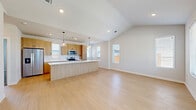 Located in Frisco, TX, this single-story, 2-bedroom, 2-bathroom home offers a thoughtfully designed open-concept layout with contemporary finishes throughout. The living room impresses with vaulted ceilings and recessed lighting, while light wood-tone flooring flows seamlessly from the entry through the main living areas, creating a bright and airy ambiance enhanced by multiple windows.

The kitchen is a standout feature, showcasing light wood flat-panel cabinetry, white quartz countertops, a tiled backsplash, and stainless steel appliances including a French door refrigerator, electric range, and microwave. A peninsula with pendant lighting connects the kitchen to the living space, making it ideal for entertaining.

Both bedrooms are carpeted and include ceiling fans and ample natural light. The spacious primary bedroom is served by a well-appointed en-suite bathroom featuring warm wood vanity cabinetry, white quartz countertops, a frameless glass walk-in shower, and light wood flooring. Each bedroom benefits from dedicated closet space with built-in shelving and hanging rods.

The hallway connects all rooms efficiently, and the home also features a private backyard with a grassy lawn, a concrete step entry, and board-and-batten exterior siding — a functional outdoor space ideal for relaxation.