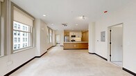 Located on the seventh floor at 929 Walnut St in downtown Kansas City, this 2-bedroom, 2-bathroom unit offers a well-designed, single-level layout with a clean, contemporary aesthetic throughout. The open-concept kitchen serves as the heart of the home, featuring a large island with a white quartz countertop, an undermount sink, warm natural wood cabinetry, white upper cabinets, and a full suite of stainless steel appliances including a refrigerator, range, and built-in microwave. Recessed lighting and tile flooring complete the kitchen's modern appeal. The living area extends naturally from the kitchen, bathed in natural light from multiple windows framing views of the surrounding downtown cityscape. Both bedrooms are generously sized, finished with plush patterned carpet, neutral walls, and built-in sliding closets. The primary bedroom enjoys its own windows with urban views, adding to its bright, airy character. Each of the two bathrooms is appointed with warm wood vanities, white countertops, tile flooring, and sleek glass-enclosed walk-in showers with matte black hardware accents — a refined, modern touch carried consistently throughout the unit.