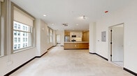 Located on the seventh floor at 929 Walnut St in downtown Kansas City, this 2-bedroom, 2-bathroom unit offers a well-designed, single-level layout with a clean, contemporary aesthetic throughout. The open-concept kitchen serves as the heart of the home, featuring a large island with a white quartz countertop, an undermount sink, warm natural wood cabinetry, white upper cabinets, and a full suite of stainless steel appliances including a refrigerator, range, and built-in microwave. Recessed lighting and tile flooring complete the kitchen's modern appeal. The living area extends naturally from the kitchen, bathed in natural light from multiple windows framing views of the surrounding downtown cityscape. Both bedrooms are generously sized, finished with plush patterned carpet, neutral walls, and built-in sliding closets. The primary bedroom enjoys its own windows with urban views, adding to its bright, airy character. Each of the two bathrooms is appointed with warm wood vanities, white countertops, tile flooring, and sleek glass-enclosed walk-in showers with matte black hardware accents — a refined, modern touch carried consistently throughout the unit.