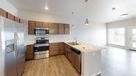 Located at 4570 49th Ave S in Fargo, North Dakota, this single-floor unit offers a well-designed, open-concept layout that promotes a seamless flow between living and kitchen spaces. The kitchen is a functional centerpiece, equipped with rich dark wood cabinetry, light quartz countertops, and a full suite of stainless steel appliances including a refrigerator with ice maker, electric range, built-in microwave, and dishwasher. A peninsula with an integrated sink provides additional workspace and casual seating potential, while pendant lighting above adds a clean, contemporary touch. Wood-style flooring runs through the main living and kitchen areas, creating a warm, cohesive aesthetic.

The living area is open and inviting, benefiting from natural light brought in through multiple windows. Bedroom spaces feature neutral carpet, generous natural light from large windows with blinds, and a calm, understated color palette. The bathroom includes a full tub and shower combination with clean white surround and chrome fixtures. A dedicated laundry room houses a full-size washer and dryer with overhead shelving for added storage. Throughout the unit, neutral tones and clean finishes contribute to a bright, move-in-ready atmosphere.