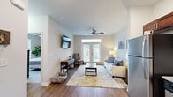 Located in Arden, NC, this well-appointed one-bedroom, one-bathroom unit offers a thoughtfully designed single-floor layout that maximizes every square foot. The living room serves as the heart of the space, featuring durable hardwood-style flooring, a ceiling fan, and a set of French doors topped with a transom window that floods the room with natural light and provides outdoor views. A wall-mounted TV and a cozy seating nook add to the room's functionality. The kitchen is outfitted with rich dark cabinetry, granite-style countertops, stainless steel appliances including an electric range, microwave, and refrigerator, and recessed lighting overhead. The bedroom is a comfortable retreat with plush carpeting, a ceiling fan, and generous windows that invite natural light and views of the surrounding landscape. A dedicated closet provides practical storage. The bathroom features warm wood-tone cabinetry, a granite-topped vanity with an undermount sink, and hardwood-style flooring that ties the space together cohesively. Neutral tones and clean finishes throughout lend a calm, modern aesthetic to this efficiently designed Arden residence.