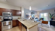 Located in Menomonee Falls, WI, this one-bedroom, one-bathroom residence offers a well-designed, single-floor layout that makes efficient use of its space. The open-concept living and kitchen area serves as the heart of the home, where rich dark-wood cabinetry pairs elegantly with granite countertops and a full suite of stainless steel appliances, including a refrigerator, range, and built-in microwave. Light wood-style flooring runs through the kitchen and into the living area, adding warmth and continuity. A peninsula with seating provides a natural transition between the kitchen and living room, which is bathed in natural light from a sliding glass door that opens to a private balcony. The living room features a soothing neutral palette accented by a blue feature wall, creating a calm and inviting atmosphere. The bedroom is a comfortable retreat with plush carpeting, a generously sized window overlooking the outdoors, and a dedicated closet for storage. The full bathroom includes a vanity with dark wood cabinetry, a combination tub and shower, and light wood-style flooring that complements the overall design aesthetic. Clean lines, thoughtful finishes, and an abundance of natural light give this residence a modern, polished character throughout.
