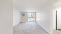 Located at 2000 S University Blvd in Denver, CO, this 2-bedroom, 2-bathroom residence offers a practical and comfortable single-floor layout. The living room features neutral carpet flooring, clean white walls, and a large window with vertical blinds that invites natural light and outdoor views of surrounding trees. A wall-mounted HVAC unit and baseboard heating are present throughout, ensuring year-round comfort. The layout connects the living area to a designated dining room and a functional kitchen equipped with standard appliances and wood-look flooring. Both bedrooms are carpeted and feature ceiling fans with integrated lighting. The primary bedroom includes a closet with bifold doors, while additional closets throughout the unit provide generous storage. A hallway connects the bedrooms to two full bathrooms. One bathroom features a tub/shower combination with built-in shelving, a white vanity with ample counter space, a mirrored medicine cabinet, and wood-look tile flooring. The second bathroom offers a similarly clean, bright design with a wide vanity countertop and mirror. With four closets total and a straightforward floor plan, this residence delivers efficient use of space in a convenient Denver location.
