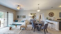 Located at 10971 Southgate Manor Dr in Louisville, Kentucky, this single-floor residence offers a thoughtfully designed layout that balances comfort and functionality. The open-concept living and dining area is carpeted and bathed in natural light from a sliding glass door, creating a warm and inviting atmosphere. The living space features a ceiling fan and flows seamlessly into a dedicated dining area with a pendant light overhead, ideal for everyday meals or entertaining.

The kitchen is equipped with stainless steel appliances, including a refrigerator, range, and microwave, complemented by gray cabinetry and wood-look flooring that adds a contemporary touch.

Both bedrooms are generously sized, each featuring plush carpet, vaulted ceilings, and direct access to walk-in closets, providing ample storage. The two bathrooms are finished with wood-look flooring, and include a vanity and a shower-tub combination. One bathroom showcases a distinctive navy blue vanity, adding a stylish accent to the neutral palette throughout the home.

A dedicated laundry room with a full-size washer and dryer adds everyday convenience. Neutral wall tones and consistent finishes throughout the space create a cohesive, move-in-ready environment suited for comfortable single-floor living.
