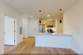 Located at 431 Dr. Martin Luther King Jr. Boulevard in East Orange, NJ, this modern single-floor residence offers a thoughtfully designed layout with one bedroom, one bathroom, a den, and in-unit laundry. Light-toned hardwood flooring runs throughout, complementing the clean white walls and creating a bright, cohesive aesthetic.

The open-concept kitchen and living area serves as the heart of the home. The kitchen features a large central island with a sleek quartz countertop, stainless steel appliances including a refrigerator, range, and microwave, light wood cabinetry extending to the ceiling, and stylish pendant lighting overhead. A wall-mounted mini-split unit provides additional climate control to the living area.

The spacious bedroom offers a generous footprint, natural light through a large window with urban views, a wall-mounted PTAC unit, and a double-door closet for ample storage. Two additional closets are found elsewhere in the residence. The den provides flexible space suitable as a home office or additional lounge area, also equipped with its own wall-mounted PTAC unit.

The full bathroom is finished with tile flooring, a sleek single-sink vanity with under-cabinet storage, a large mirror, and chrome fixtures. Dedicated laundry accommodations round out this well-appointed, move-in-ready residence.