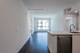 This contemporary single-floor residence showcases a clean, modern design defined by crisp white walls, dark hardwood flooring, and an abundance of natural light throughout. The open-concept living and dining area flows seamlessly from the kitchen, offering a bright and airy atmosphere enhanced by large windows with views of the surrounding urban streetscape. Track lighting overhead adds a polished, functional touch to the living space.

The kitchen is well-appointed with sleek white cabinetry extending to the ceiling, white quartz countertops, a subway-tile backsplash, and a full suite of stainless steel GE appliances, including a refrigerator, range, over-the-range microwave, and dishwasher. A kitchen island with an undermount sink adds additional workspace and a natural transition to the living area.

The bedrooms are generously sized, each featuring dark hardwood floors, white walls, and large windows that invite natural light and provide views of the neighboring buildings. The two full bathrooms mirror the home's modern aesthetic, with white vanities, illuminated mirrors, quartz countertops, neutral large-format tile flooring, and full tub-shower combinations with tiled surrounds.

Completing the home is a dedicated in-unit laundry closet housing a stacked GE washer and dryer, adding everyday convenience to this thoughtfully designed residence.