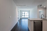 This contemporary single-floor residence showcases a clean, modern design defined by crisp white walls, dark hardwood flooring, and an abundance of natural light throughout. The open-concept living and dining area flows seamlessly from the kitchen, offering a bright and airy atmosphere enhanced by large windows with views of the surrounding urban streetscape. Track lighting overhead adds a polished, functional touch to the living space.

The kitchen is well-appointed with sleek white cabinetry extending to the ceiling, white quartz countertops, a subway-tile backsplash, and a full suite of stainless steel GE appliances, including a refrigerator, range, over-the-range microwave, and dishwasher. A kitchen island with an undermount sink adds additional workspace and a natural transition to the living area.

The bedrooms are generously sized, each featuring dark hardwood floors, white walls, and large windows that invite natural light and provide views of the neighboring buildings. The two full bathrooms mirror the home's modern aesthetic, with white vanities, illuminated mirrors, quartz countertops, neutral large-format tile flooring, and full tub-shower combinations with tiled surrounds.

Completing the home is a dedicated in-unit laundry closet housing a stacked GE washer and dryer, adding everyday convenience to this thoughtfully designed residence.