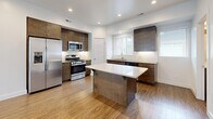 Located at 425 E 700 S in Salt Lake City, Utah, this modern three-bedroom, three-bathroom home is thoughtfully laid out across three floors. The entry-level garage provides convenient attached parking with built-in shelving for additional storage. The main living floor offers an open-concept kitchen and living area bathed in natural light from large windows. The kitchen is a standout, featuring rich dark wood cabinetry, white quartz countertops, a central island with bar seating, subway tile backsplash, stainless steel appliances, and warm hardwood-style flooring. The adjacent living area continues the same flooring, creating a seamless, expansive feel with recessed lighting overhead. Carpeted bedrooms are found on the upper floor, each offering a clean, neutral palette and ceiling fans for comfort. The primary bedroom provides a generous private retreat. The three bathrooms maintain a consistent modern aesthetic with dark wood vanities, white quartz surfaces, and wood-look tile flooring. A carpeted staircase with a sleek metal handrail connects all three levels. Throughout the home, crisp white walls, recessed lighting, and consistent finishes create a cohesive, move-in-ready environment.