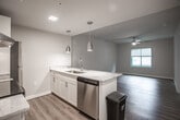 Located at 3200 W Broad St in Richmond, Virginia, this single-floor unit offers a well-designed layout that balances modern finishes with everyday functionality. The open-concept living and dining area is bathed in natural light from large windows offering views of the surrounding cityscape, and features smooth wood-look flooring and ceiling fans that contribute to a comfortable, airy atmosphere. The kitchen flows seamlessly from the living space and is outfitted with white cabinetry, granite-style countertops, a classic white subway tile backsplash, stainless steel appliances including a range and refrigerator, and pendant lighting that adds a contemporary touch. The bedroom continues the cohesive aesthetic with matching wood-look flooring, a ceiling fan, and a window that brings in ample natural light. The bathroom area showcases large-format tile flooring, white vanity cabinetry topped with marble-style countertops, and a thoughtfully organized layout. Additional cabinetry with warm wood tones and open shelving provides flexible storage. The overall design palette of neutral tones, clean lines, and quality finishes creates a polished and inviting living environment well-suited to the vibrant West Broad Street corridor.