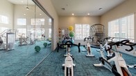 Located on Carl D Silver Parkway in Fredericksburg, Virginia, this single-floor fitness center is a comprehensively outfitted facility designed to support a wide range of workout routines. The main cardio floor impresses with soaring ceilings, pendant lighting, and large windows that flood the space with natural light. Rows of TRUE-brand treadmills, ellipticals, and recumbent bikes are arranged across teal-toned carpet, with multiple wall-mounted televisions keeping users entertained during their sessions. Full-length mirrors line the walls, amplifying the sense of openness throughout.

A dedicated free weights area features a complete dumbbell rack, barbells with weight plates, and floor-to-ceiling mirrors, providing ample space for strength training. Adjacent to this is a functional training zone with rubber flooring, a cable machine, battle ropes, plyo boxes in varying heights, stability balls, and a wall-mounted TV, making it ideal for high-intensity and cross-training workouts.

A separate cycling studio houses multiple TRUE spin bikes on vibrant teal carpet, with a glass partition offering views into the main gym floor. Natural light enters through a glass exterior door, creating an energizing environment. Throughout the facility, the design maintains a clean, modern aesthetic with neutral walls, recessed lighting, and thoughtful equipment placement that maximizes usability and flow.
