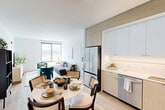 Located at 77 Bruton St on Treasure Island in San Francisco, this thoughtfully designed 2-bedroom, 2-bathroom residence offers a bright, contemporary living experience. The open-concept kitchen, dining, and living area serves as the heart of the home, featuring light wood-finish cabinetry, white upper cabinets, stainless steel appliances including a full-size refrigerator and dishwasher, and a clean white tile backsplash. A round dining table sits adjacent to the kitchen, flowing naturally into the spacious living area, which is bathed in natural light from large floor-to-ceiling windows with sweeping views of the surrounding landscape and bay. Light hardwood-style flooring runs throughout, enhancing the airy, cohesive feel. The primary bedroom is generously sized, offering expansive corner windows with scenic outdoor views, while the second bedroom provides a comfortable, well-lit retreat. Each bedroom is served by its own closet, including a walk-in with built-in wire shelving. The two bathrooms are finished with large-format tile, wood-toned vanities, undermount sinks, and glass-enclosed showers. The overall design emphasizes clean lines, neutral tones, and an abundance of natural light throughout.