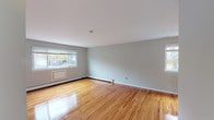 Located at 35 Penataquit Avenue in Bay Shore, NY, this single-floor unit at Mid Island Apartments offers a well-designed layout with consistent finishes throughout. Polished hardwood floors extend across the living areas and bedrooms, lending warmth and a classic aesthetic to the space. The living area is generously sized, with multiple windows fitted with blinds that allow for abundant natural light, complemented by baseboard heating and a ceiling fan for year-round comfort. The updated kitchen features white shaker-style cabinetry, marble-look countertops, a neutral tile backsplash, and a full suite of stainless steel appliances including a gas range, dishwasher, refrigerator, and built-in microwave, all set on light luxury vinyl flooring. The bedrooms are well-proportioned, each with hardwood floors, large windows with outdoor views, and baseboard heating. One bedroom includes a walk-in closet, adding practical storage. The bathroom is clean and functional, featuring white tile surround, a tub-shower combination, and a marble-top vanity with chrome fixtures. The unit's neutral gray palette throughout creates a cohesive, move-in-ready atmosphere suited to a variety of living styles.