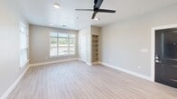 This thoughtfully designed single-floor residence offers a comfortable and functional layout across one bedroom, one bathroom, and a combined kitchen and living area. Light wood-style flooring runs consistently throughout the space, lending a clean and cohesive aesthetic from room to room.

The kitchen is outfitted with white cabinetry, granite countertops, stainless steel appliances including a French door refrigerator and range, and a undermount sink. Pendant lighting adds a warm accent above the countertop, complementing the recessed lighting overhead.

The open living area is bright and airy, benefiting from natural light through large windows that offer outdoor views. A ceiling fan provides additional comfort, while neutral warm-gray walls keep the palette versatile and inviting.

The bedroom is a comfortable size, featuring a window with outdoor views, ceiling fan, built-in shelving for added storage, and access to a closet. The neutral tones continue here, creating a calm and restful environment.

The bathroom features a walk-in glass-enclosed shower with floor-to-ceiling tile surround, chrome fixtures, and granite countertop finishes, delivering a clean and modern look. A hallway connects the rooms efficiently, completing this well-organized and move-in-ready floor plan.