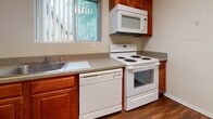 Located at 736 Camberley Circle in Towson, Maryland, this two-floor home offers a practical and comfortable layout designed for everyday living. The main level features warm hardwood-style flooring in the kitchen and bathroom areas, while plush wall-to-wall carpeting runs throughout the living spaces and bedrooms, lending a cozy feel underfoot.

The kitchen is well-appointed with warm wood cabinetry, granite-look countertops, and a full suite of white appliances including an electric range, over-the-range microwave, and dishwasher. A window above the sink brings in natural light and offers a view of the surrounding greenery. The adjacent bathroom features matching wood cabinetry, a single vanity with a white countertop, tiled walls, and a window for added ventilation and light.

The living areas are generously proportioned, with an open flow between rooms defined by architectural beam details and wide entryways. Natural light filters in through vertical-blind-covered windows throughout. The bedrooms are well-sized, with neutral walls, carpeted floors, and ample closet space including built-in shelving and hanging rods. The overall aesthetic is clean and neutral, providing a versatile canvas ready for personalization.