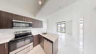 Located at 1 Curtiss Pkwy in Miami Springs, Florida, this thoughtfully designed one-bedroom, four-bathroom residence offers a clean, contemporary aesthetic throughout its well-utilized single floor. Polished marble-look porcelain tile flows seamlessly across every room, lending a bright, upscale feel to the entire space.

The open-concept kitchen and living area serves as the heart of the home. The kitchen is outfitted with rich dark-wood cabinetry, sleek quartz countertops, and a full suite of stainless steel appliances, including a French-door refrigerator, electric range, built-in microwave, and dishwasher. A peninsula with an undermount sink provides additional prep space and connects the kitchen to the airy living area, which is bathed in natural light from large, black-framed windows offering views of lush tropical greenery.

The primary bedroom is generously proportioned, featuring the same polished tile flooring, crisp white walls, and a large window with palm tree views, reinforcing the South Florida atmosphere. Two closets provide practical storage throughout the unit.

The four bathrooms are finished in a consistent modern style, featuring marble-look tile, quartz vanity tops, undermount sinks, large mirrors, and brushed gold or chrome fixtures. A hallway connects all areas efficiently, with a welcoming entry foyer completing the layout.