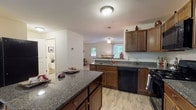 Located at 35 Hidden Oak Way in Manchester, NH, this three-floor home delivers a functional and comfortable layout across its levels. The kitchen is a standout feature, outfitted with rich dark wood cabinetry, granite countertops, black appliances including a gas range, built-in microwave, and dishwasher, along with a peninsula that provides additional prep and serving space. Light-tone flooring ties the kitchen seamlessly into the adjacent dining area, which benefits from a large picture window overlooking the surrounding greenery, filling the space with natural light. The living areas are finished with plush carpeting and neutral walls, creating a warm and inviting atmosphere throughout. The primary bedroom is generously proportioned, featuring multiple windows on two walls that frame pleasant outdoor views and allow abundant natural light. Additional bedrooms are carpeted and well-sized, each offering comfortable accommodations. The bathrooms are finished with granite-topped wood vanities and tile-style flooring, maintaining a consistent aesthetic. A half bath provides added convenience on the main level. The unfinished basement spans a substantial footprint, housing the mechanical systems and presenting excellent potential for future customization or additional living space. Set in a quiet residential neighborhood, this home combines practical design with inviting details throughout all three floors.