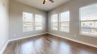 Located at 9600 Gaylord Pkwy in Frisco, TX, this well-appointed single-story home offers three bedrooms, two full bathrooms, and three closets across a thoughtfully designed floor plan. The open-concept kitchen and living area serves as the heart of the home, anchored by a large center island with granite countertops and an undermount sink, rich dark-wood cabinetry, a tile backsplash, and a full suite of stainless steel appliances. Pendant lights hang above the island, adding a stylish touch to the space. The living area features hardwood-style flooring and a generous bank of windows fitted with white blinds, flooding the room with natural light and offering views of the surrounding neighborhood. Ceiling fans are present in the main living spaces and primary bedroom, ensuring comfort throughout. The bedrooms are carpeted and neutrally toned, providing a calm and restful atmosphere, with the spacious primary bedroom offering ample room. Each bathroom is finished with granite-topped dark vanities, tile-surround tub-shower combinations, and wood-style flooring. The closets are equipped with wire shelving systems for organized storage. Soft gray walls and clean white trim carry consistently throughout, creating a cohesive and move-in-ready aesthetic.
