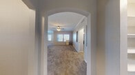 This single-story space is thoughtfully designed with a neutral color palette and a blend of practical finishes throughout. A distinctive arched entryway with decorative molding frames the main living area, which features plush carpeting, crown molding, and a ceiling fan overhead. Multiple windows allow natural light to fill the space, creating a bright and welcoming atmosphere.

The kitchen is laid out in a galley style, equipped with stainless steel appliances including a refrigerator, microwave, and range. Light wood-toned cabinetry pairs with dark granite-style countertops, and wood-look flooring adds a clean, durable surface underfoot. A pass-through counter connects the kitchen to the living area, enhancing the open feel.

The bedrooms are carpeted and generously proportioned, each with ceiling fans and ample natural light from well-placed windows. At least one bedroom includes access to a spacious walk-in closet outfitted with wire shelving systems on multiple walls, offering substantial storage capacity.

The bathrooms feature wood-look tile flooring, warm-toned cabinetry with granite-style countertops, and dual-sink vanities. One bathroom includes a tub-shower combination with tiled surrounds. Overall, the space offers a comfortable, functional layout suitable for everyday living.