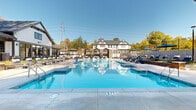 Located at 2116 Pleasant Road in Fort Mill, SC, this outdoor amenity area is a thoughtfully designed resort-style retreat that serves as a centerpiece for community recreation and relaxation. The space is anchored by a generously sized swimming pool with a shallow zero-entry wading area, offering both a leisurely lounge experience and active swimming lanes. The pool deck is finished in smooth, light-toned concrete and is lined with contemporary chaise lounges and seating arrangements, providing ample space for sunbathing and socializing under the open sky.

A standout feature of the area is the covered pavilion, constructed with brick columns and a gabled roof, housing an outdoor entertainment setup that serves as a shaded gathering spot. Adjacent to the pool, a dedicated lounge zone offers turf seating areas, umbrella-shaded chairs, and outdoor grilling stations, making it well-suited for casual outdoor dining and leisure.

The architecture of the surrounding buildings features a classic Craftsman-inspired aesthetic, with white board-and-batten siding, dark trim, and pitched rooflines that lend a cohesive, upscale character to the entire complex. Mature trees frame the perimeter, providing natural shade and a sense of seclusion. The entire outdoor space is enclosed by decorative fencing, ensuring privacy while maintaining an open, airy atmosphere throughout.