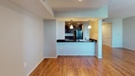 This single-floor residence offers a thoughtfully designed layout that balances functionality and comfort. The kitchen is a standout feature, showcasing dark espresso cabinetry with sleek hardware, granite-style countertops, and a full suite of black appliances including a range, microwave, and refrigerator. Recessed lighting illuminates the workspace, while a peninsula with pendant lighting creates a natural connection to the open living area, which features warm hardwood-style flooring that extends throughout the main living spaces.

The living area benefits from an open-concept connection to the kitchen, providing a sense of spaciousness and ease of flow. Pendant lights above the peninsula add a stylish focal point to the shared space.

The bedroom is generously sized and features plush carpeting, a ceiling fan with light fixture, and a window that invites natural light. A walk-in closet with built-in shelving and hanging rods provides ample storage. An additional carpeted room with a ceiling fan and window offers similar comfort and natural light.

The bathroom is finished with neutral tile flooring, a pedestal sink, and a framed mirror, creating a clean and functional space. Neutral wall tones throughout the residence contribute to a calm, cohesive ambiance.
