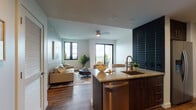 Located in the desirable Coconut Grove neighborhood of Miami, this single-floor residence at 3724 Loquat Ave offers a thoughtfully designed open-concept layout that seamlessly connects the kitchen, dining, and living areas. Rich hardwood flooring flows throughout the space, complementing the clean, contemporary aesthetic defined by crisp white walls and black-framed windows that flood each room with natural light and frame lush outdoor views.

The kitchen is a standout feature, appointed with dark espresso cabinetry, granite countertops, a spacious island with an undermount sink, and a full suite of stainless steel appliances. Adjacent to the kitchen, a compact dining nook with a round table and gold-framed mirror offers an intimate setting for meals. A dramatic dark accent wall adds a bold design element to the kitchen and living area transition.

The living room is generously proportioned, with large sliding glass doors opening to a private balcony offering sweeping treetop views — a hallmark of Miami's Coconut Grove canopy.

The bedrooms are serene and well-lit, each featuring hardwood floors, black-framed windows, and ample closet space. The bathroom is finished with granite countertops, warm-toned wall tile, and modern recessed lighting, providing a clean and functional retreat.