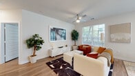 This thoughtfully designed single-floor residence offers a seamless blend of modern aesthetics and functional living. The open-concept layout connects the living, dining, and kitchen areas, creating an inviting and cohesive flow throughout the space. Warm hardwood-style flooring runs consistently throughout, tying each room together.

The living area is bright and airy, featuring large windows with exterior views, a ceiling fan, and ample room for comfortable seating arrangements. Adjacent to it, the kitchen stands out with two-tone cabinetry — dark lower cabinets paired with white uppers — a mosaic tile backsplash, stainless steel appliances, and a generous island with a waterfall countertop illuminated by geometric pendant lighting. A dining area sits nearby, benefiting from the same natural light.

The bedroom is calm and well-proportioned, with a large window allowing in abundant natural light and views of the surrounding exterior. The primary bathroom impresses with dual-sink vanity, dark cabinetry with ample storage, a soaking tub with tile surround, and direct access to a walk-in closet. A secondary bathroom features a tub-shower combination with large-format tile.

The entry hallway, accented by recessed lighting and clean white millwork, provides a polished welcome to the residence.
