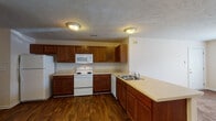 Located at 2580 Cumberland Creek Dr in Fayetteville, NC, this single-floor home offers a practical and comfortable layout designed for everyday living. The kitchen is well-appointed with rich, warm-toned wood cabinetry, ample counter space, a double-basin sink, and white appliances including a range, built-in microwave, dishwasher, and refrigerator. Durable wood-look flooring runs throughout the kitchen and dining areas, adding warmth and ease of maintenance. The open layout connects the kitchen to a dining area with a chandelier and a spacious living area finished with plush carpeting and a ceiling fan. Multiple bedrooms feature soft carpet flooring, ceiling fans, and windows that bring in natural light with views of surrounding greenery. Closet space is provided in the bedrooms, including a reach-in closet in one of the larger rooms. The home includes two bathrooms, each outfitted with wood-toned vanity cabinetry, light countertops, and wood-look flooring. One bathroom features a tub/shower combo, while the other offers a vanity with a large mirror and wall-mounted cabinet. Neutral wall tones and textured ceilings are consistent throughout, creating a cohesive and move-in-ready atmosphere.