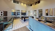 Located at 305 W Commerce St in Dallas, Texas, this single-floor amenity space is designed to deliver an upscale, social atmosphere with a variety of entertainment and lounge areas. Soaring double-height ceilings define the open layout, creating an expansive, airy feel throughout the space. Large windows and glass entry doors invite abundant natural light while offering views of the surrounding exterior.

The main lounge area is anchored by a large-format media wall with a mounted flat-screen display, complemented by plush sectional and sofa seating accented with eclectic throw pillows. Reclaimed wood wall accents and decorative slatted wood paneling add warmth and texture, balanced by contemporary artwork and sculptural coffee tables made of natural materials.

An adjacent game area features a full-size billiards table centered on a geometric-patterned tile floor, surrounded by additional seating and high-top bar tables with stools — ideal for casual gatherings. The open floor plan allows these zones to flow seamlessly into one another.

A dedicated refreshment station rounds out the space, outfitted with dark stone-textured wall cladding, bold black marble countertops, a smart stainless steel refrigerator, and a fully stocked coffee and creamer bar. The cohesive design blends industrial and contemporary elements throughout, creating a dynamic and functional communal environment.