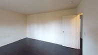 Located at 498 Plaza Blvd in Morrisville, PA, this single-floor unit offers a clean, functional layout with a cohesive design throughout. Rich dark hardwood flooring flows consistently across the living areas and bedrooms, providing a striking contrast against the neutral, light-toned walls that give the space a bright and open feel.

The living area is generously sized, featuring a window with blinds that allows natural light to fill the room. A wall-mounted air conditioning and heating unit ensures year-round comfort, complemented by baseboard heating along the perimeter. An entry door opens directly into this main living space, offering convenient access.

The kitchen is designed for efficiency, featuring dark cabinetry, a gas range, built-in microwave, full-sized refrigerator, and a single-basin sink beneath a window. Light wood-look flooring in the kitchen contrasts with the darker floors found elsewhere in the unit.

The bedrooms are quiet and well-proportioned, each finished with the same dark hardwood flooring and neutral walls. One bedroom features a ceiling light fixture, while the rooms are served by paneled interior doors throughout.

The bathroom is neatly appointed with a vanity, toilet, and a full tub-shower combination with a curtain rod, alongside a window with blinds providing ventilation and natural light. Overall, the unit presents a practical and well-maintained living environment.