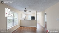 Located at 116 Waterway Dr in Spring Lake, NC, this single-story, 3-bedroom, 2-bathroom home offers a well-organized layout designed for comfortable everyday living. Rich hardwood flooring flows throughout the main living areas and hallways, complemented by neutral-toned walls and textured ceilings that give the home a warm, inviting character.

The open-concept kitchen is a functional centerpiece, featuring white cabinetry with modern hardware, light granite countertops, a breakfast bar peninsula, and black appliances including a range, dishwasher, and refrigerator. A window above the sink brings in natural light, and the kitchen opens directly to the combined dining and living area. The living room is bright and spacious, highlighted by a sliding glass door that leads to an outdoor deck with views of the surrounding greenery.

Three bedrooms provide ample accommodation, with the generously sized primary bedroom offering notable square footage and a large window with outdoor views. The secondary bedrooms are carpeted and feature windows that allow natural light to filter in. Both bathrooms are well-appointed with white vanities, granite countertops, and tub-shower combinations. Six closets throughout the home ensure abundant storage. A utility room and two hallways complete the practical, efficiently arranged floor plan.