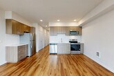 This well-appointed one-bedroom, one-bathroom unit at 2721 Wetmore Ave in Everett, WA offers a thoughtfully designed open-concept layout across a single floor. Warm wood-look flooring flows consistently throughout the entire space, creating a cohesive and inviting atmosphere.

The combined living, dining, and kitchen area forms the heart of the unit. The modern kitchen is outfitted with stainless steel appliances — including a refrigerator, range, dishwasher, and over-the-range microwave — complemented by two-tone wood cabinetry, a white subway tile backsplash, and clean white countertops. Recessed lighting illuminates the space efficiently.

A long hallway connects the main living area to the private quarters, lined with multiple closets offering generous storage throughout. The bedroom is a bright, serene retreat featuring large floor-to-ceiling windows that frame views of the surrounding Everett cityscape and fill the room with natural light. A private balcony accessible from the living area extends the living space outdoors with additional city views.

The full bathroom is clean and functional, featuring a soaking tub with shower, a wood-toned vanity with a white countertop, and matching wood-look flooring that ties the space together cohesively.