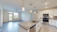 This well-appointed 2-bedroom, 2-bathroom single-story home in Houston, TX offers a thoughtfully designed open-concept layout. The kitchen serves as the centerpiece of the home, showcasing a large granite-topped island with a stainless steel sink and pendant lighting overhead, complemented by crisp white shaker cabinetry, a decorative tile backsplash, and a full suite of stainless steel appliances including a refrigerator, range, microwave, and dishwasher. Light wood-look flooring flows throughout the main living areas, enhancing the bright and airy feel. The living room is spacious and welcoming, featuring a ceiling fan and access to a private patio with outdoor views. Both bedrooms are carpeted and equipped with ceiling fans and natural light from large windows. The generously sized primary bedroom includes a walk-in closet with built-in shelving and hanging rods offering ample organization. The primary bathroom features a glass-enclosed walk-in shower with large-format tile, while the secondary bathroom offers a tiled tub-shower combination and granite vanity. Additional highlights include four closets for storage, a dedicated laundry area, and a cohesive modern design throughout the home.