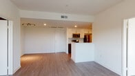 This well-appointed single-floor residence offers a clean, contemporary design with a thoughtfully laid-out floor plan. The open-concept living and dining area is finished with warm wood-tone luxury vinyl plank flooring, crisp white walls, and recessed lighting complemented by a track light fixture, creating a bright and welcoming atmosphere.

The kitchen flows seamlessly from the main living space and features a peninsula with a white quartz-style countertop that serves as both a workspace and casual dining area. White upper cabinetry is paired with rich dark wood lower cabinets, and the kitchen is fully equipped with stainless steel appliances, including a gas range, built-in microwave, and a full-size refrigerator. A subtle tile backsplash adds a refined finishing touch.

The bedroom is carpeted for comfort and receives generous natural light through a sliding window that frames views of trees and the surrounding neighborhood beyond.

The bathroom is elegantly elongated, featuring large-format tile flooring, a double-sink vanity with dark wood cabinetry and illuminated mirrors, and a combined tub and shower enclosed with a sliding glass door.

Overall, the space presents a modern, move-in-ready aesthetic with quality finishes and a functional layout designed for comfortable everyday living.