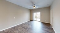 Located at 2239 Charlestown Rd in New Albany, Indiana, this one-bedroom, one-bathroom unit offers a thoughtfully designed layout across a single floor. The open-concept living, dining, and kitchen area forms the heart of the unit, finished with rich hardwood-style flooring that extends throughout the main spaces. The kitchen is well-appointed with white shaker-style cabinetry, granite-look countertops, and a full suite of stainless steel appliances including a refrigerator, gas range, microwave, and dishwasher. The living area is bright and airy, centered around a ceiling fan and anchored by sliding glass doors that open onto a private balcony with outdoor views. The bedroom offers plush carpeting, a ceiling fan, a dedicated window for natural light, and access to multiple closets for ample storage. The bathroom features a white vanity with a large mirror, clean tile work, and direct access to the bedroom. A dedicated laundry room with washer/dryer hookups, wire shelving, and hardwood-style flooring adds everyday convenience. Neutral wall tones and clean white trim throughout lend the space a modern, move-in-ready aesthetic.
