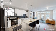 Located at 900 Willow Dr in Chapel Hill, NC, this well-appointed 2-bedroom, 2-bathroom residence offers a thoughtfully designed single-level layout. The open-concept kitchen and living area serves as the heart of the home, showcasing crisp white cabinetry, a striking dark herringbone tile backsplash, stainless steel appliances, and a central island with seating illuminated by a trio of black pendant lights. Light wood-style flooring flows throughout, enhancing the bright, airy atmosphere. The living room features large floor-to-ceiling windows and a glass-panel door opening to a private balcony, flooding the space with natural light. The primary bedroom offers a ceiling fan, a dedicated workspace, and direct access to its en-suite bathroom, which includes a walk-in glass-enclosed shower with herringbone tile, a wood-toned vanity with white countertop, and a walk-in closet with wire shelving. The second bedroom is equally comfortable, with dual windows and a ceiling fan. Two well-organized closets provide generous storage throughout. The unit combines modern finishes with a neutral color palette, creating a clean, contemporary ambiance.