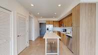 Located at 19 NE First Ct in Dania Beach, FL, this modern single-floor residence offers three bedrooms and two bathrooms with a clean, contemporary design throughout. Large-format tile flooring runs seamlessly across the living areas, reflecting natural light and reinforcing the open, airy feel of the space.

The kitchen and living room share an open-concept layout, anchored by a well-appointed kitchen featuring warm wood-tone cabinetry, white quartz countertops, white subway tile backsplash, and a full suite of stainless steel appliances including a refrigerator with ice maker, range, microwave, and dishwasher. Recessed lighting illuminates the space efficiently.

The bedrooms are bright and generously proportioned, with floor-to-ceiling sliding glass doors that open to private balconies offering open urban views of Dania Beach. Ceiling fans are installed in the bedrooms for added comfort.

The bathrooms are finished with a cohesive modern aesthetic, featuring wood-tone vanities with quartz countertops and marble-look tile surrounding a soaking tub. A hallway and closet provide practical storage and circulation throughout the home. The overall ambiance is clean, bright, and move-in ready, reflecting a contemporary South Florida residential style.